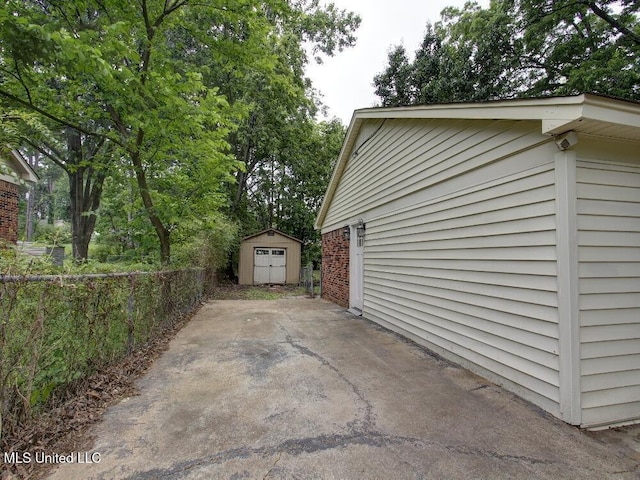 view of side of property with a shed, a patio area, an outdoor structure, and fence