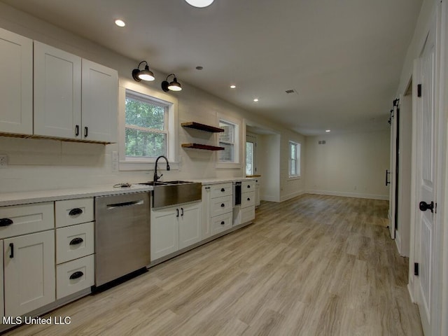kitchen featuring stainless steel dishwasher, a sink, light wood finished floors, white cabinets, and recessed lighting