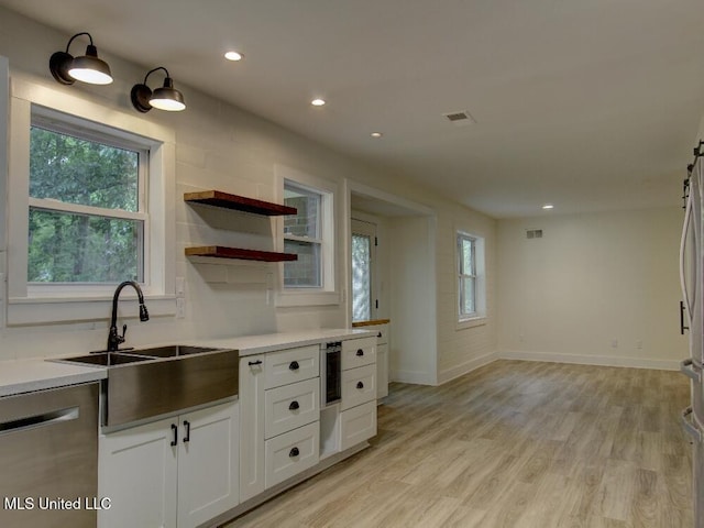 kitchen featuring appliances with stainless steel finishes, white cabinetry, light wood-type flooring, baseboards, and light countertops
