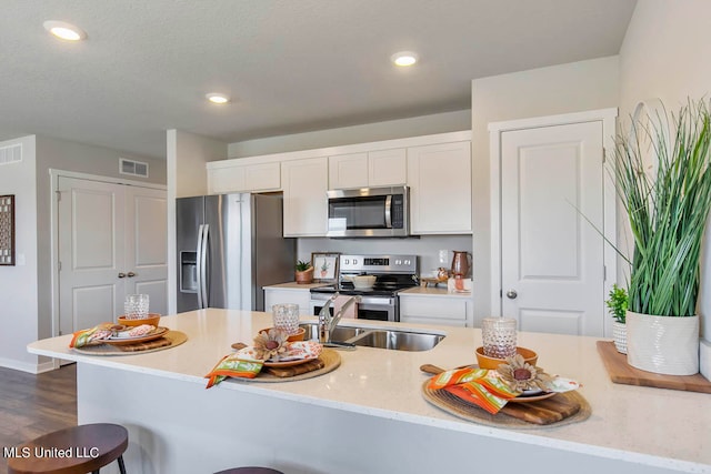 kitchen featuring white cabinets, dark hardwood / wood-style flooring, appliances with stainless steel finishes, a textured ceiling, and light stone counters