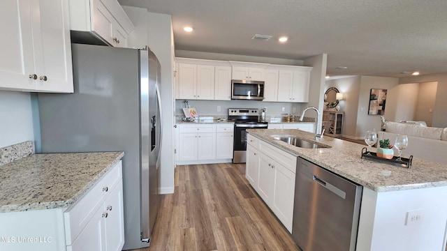 kitchen featuring visible vents, light wood-type flooring, a sink, white cabinets, and stainless steel appliances