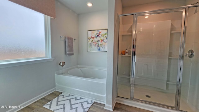 bathroom featuring wood finished floors, a garden tub, and a stall shower
