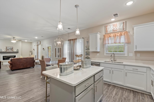 kitchen with white cabinetry, sink, a center island, pendant lighting, and light hardwood / wood-style floors