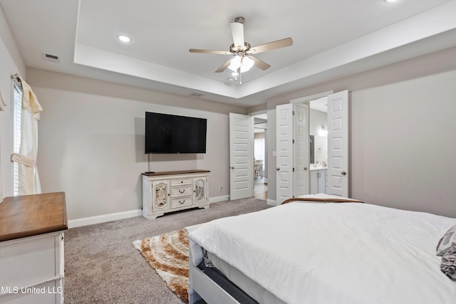 bedroom with carpet, ceiling fan, connected bathroom, and a tray ceiling