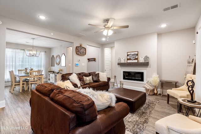 living room with ceiling fan with notable chandelier and light wood-type flooring