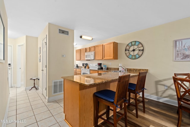 1664 Beach Blvd Unit 90, Biloxi, MS 39531 - kitchen with white appliances, baseboards, dark stone countertops, and a peninsula