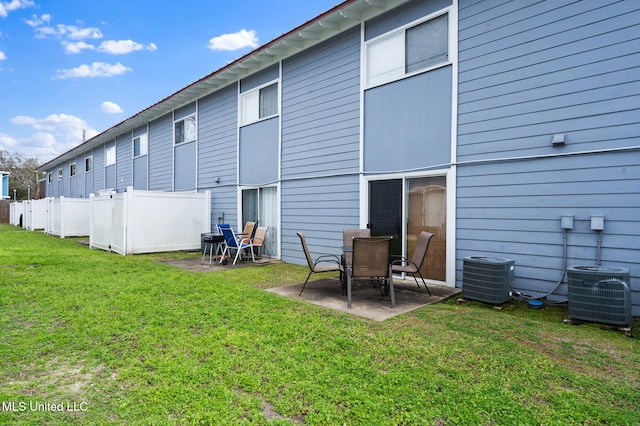 rear view of property with cooling unit, a patio area, and a lawn