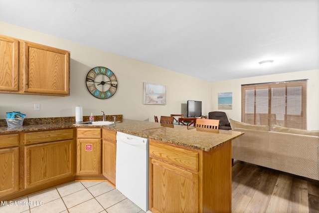 kitchen featuring sink, light hardwood / wood-style flooring, kitchen peninsula, white dishwasher, and stone countertops