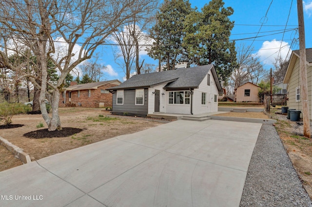 ranch-style home featuring driveway, roof with shingles, and a chimney