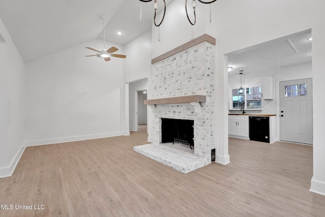 unfurnished living room featuring light wood-style flooring, a brick fireplace, attic access, and baseboards