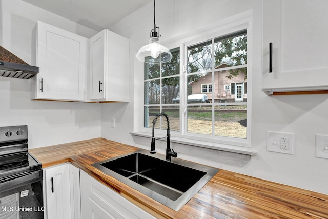 kitchen featuring black / electric stove, wall chimney exhaust hood, white cabinetry, wood counters, and a sink