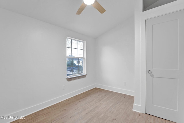 spare room featuring vaulted ceiling, light wood-style floors, baseboards, and ceiling fan