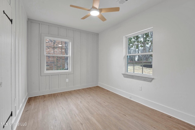 spare room featuring plenty of natural light, a ceiling fan, light wood-type flooring, and baseboards