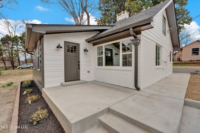 doorway to property featuring brick siding and a chimney