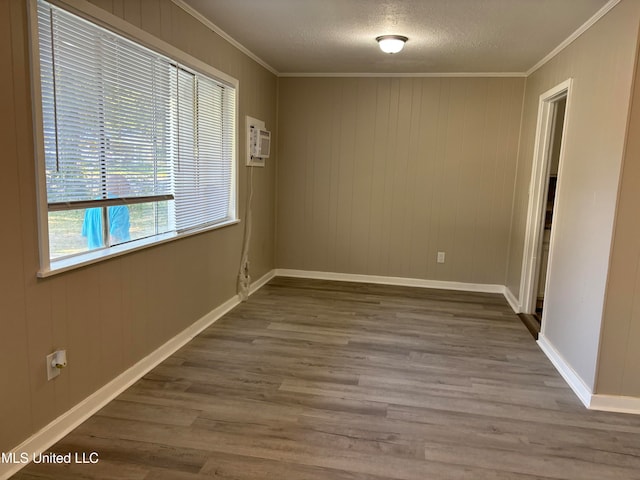 spare room featuring an AC wall unit, dark hardwood / wood-style flooring, and crown molding