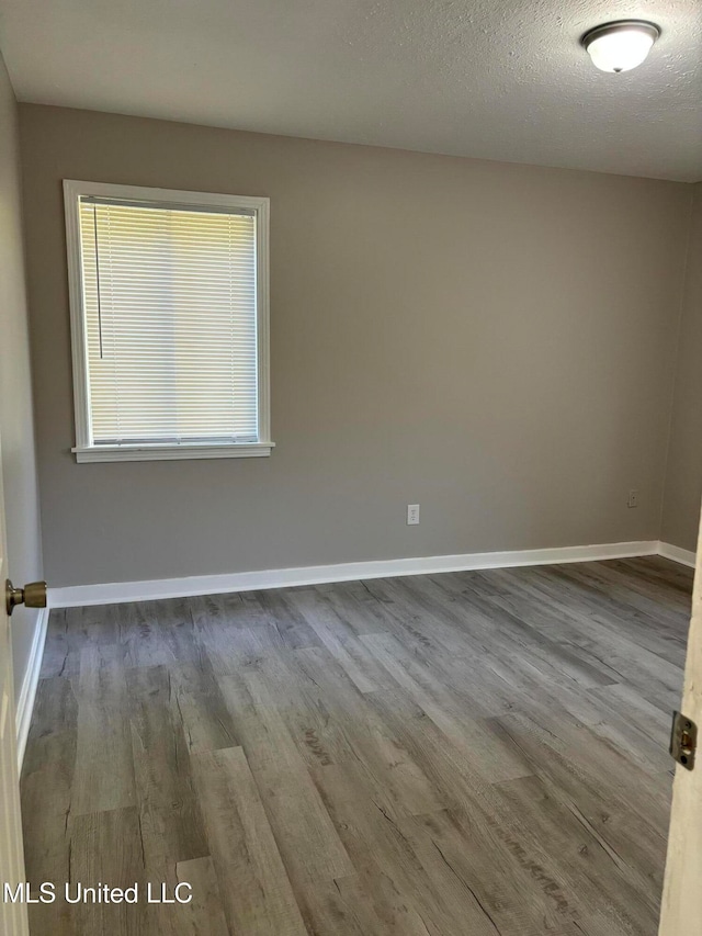 unfurnished room with hardwood / wood-style flooring and a textured ceiling