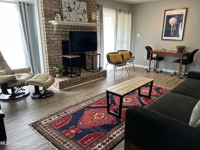 living area featuring a fireplace, wood finished floors, and baseboards