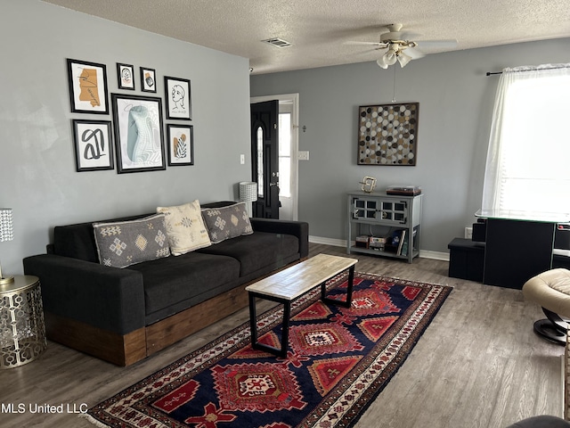 living area with a textured ceiling, visible vents, and wood finished floors