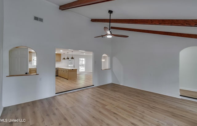 551 Holly Bush Rd, Brandon, MS 39047 - unfurnished living room featuring arched walkways, beamed ceiling, light wood-style flooring, a ceiling fan, and high vaulted ceiling