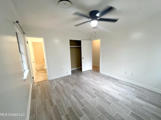 unfurnished bedroom featuring ensuite bath, ceiling fan, a textured ceiling, light hardwood / wood-style floors, and a closet