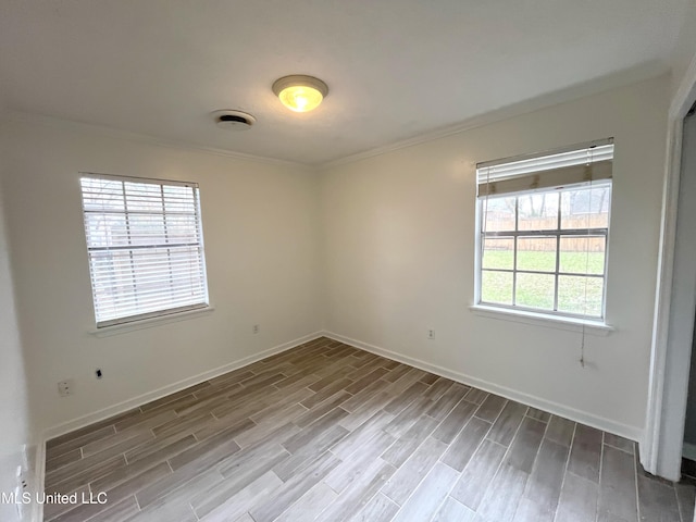 spare room featuring hardwood / wood-style flooring, plenty of natural light, and crown molding