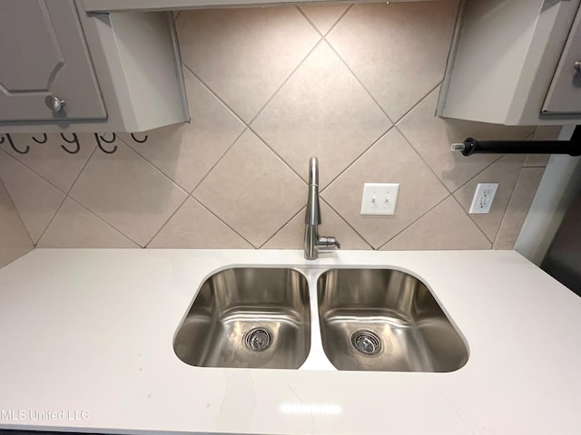 details featuring backsplash, gray cabinets, and sink