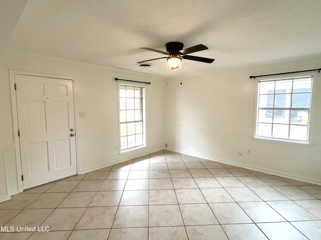 tiled spare room featuring ceiling fan and crown molding