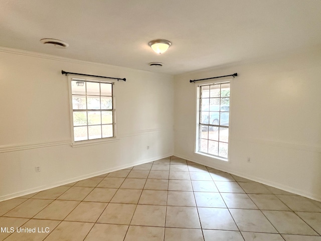 tiled empty room with a healthy amount of sunlight and ornamental molding