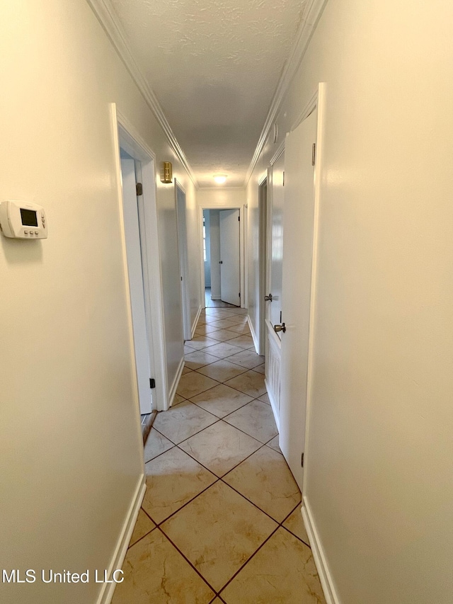 hallway with light tile patterned floors, a textured ceiling, and ornamental molding