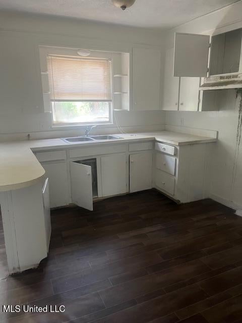 kitchen with white cabinetry, dark wood-type flooring, a sink, and light countertops