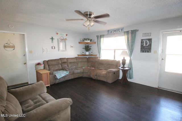 living room featuring dark hardwood / wood-style flooring, ceiling fan, and a textured ceiling