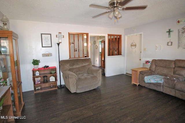 living room featuring ceiling fan, dark wood-type flooring, and a textured ceiling