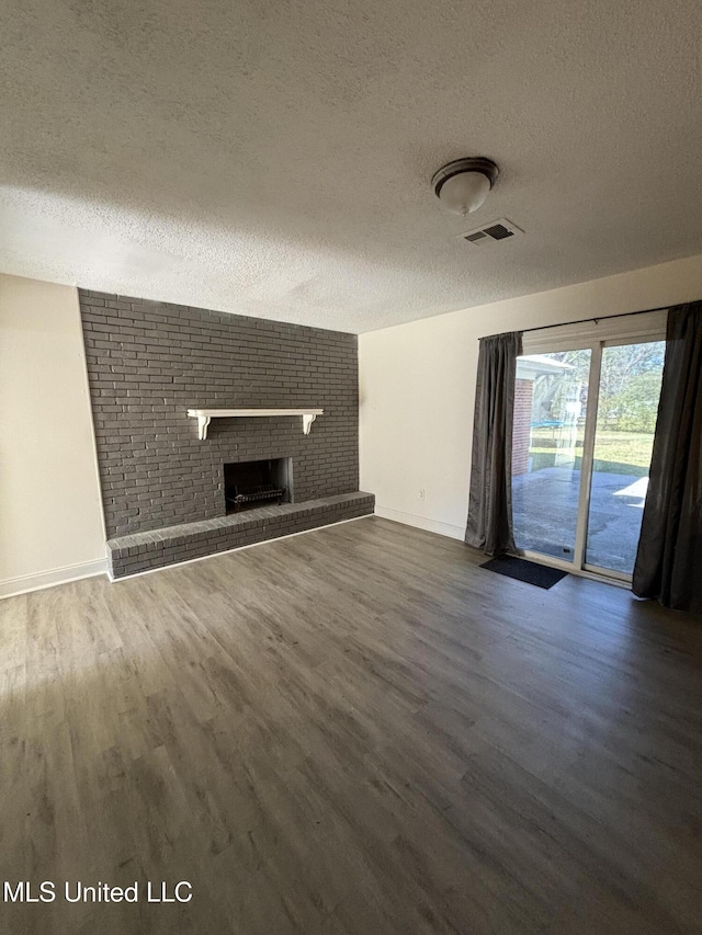 unfurnished living room featuring a brick fireplace, dark hardwood / wood-style floors, and a textured ceiling