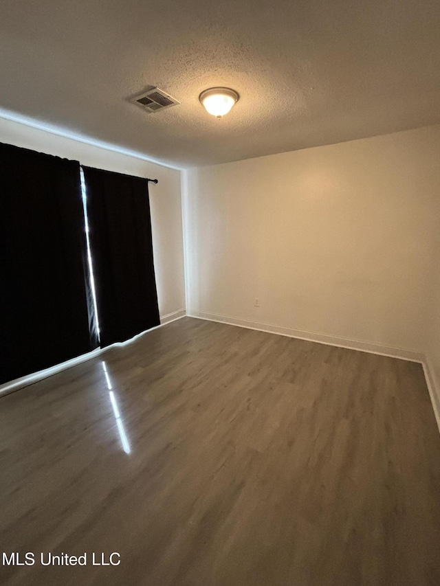 empty room featuring hardwood / wood-style flooring and a textured ceiling