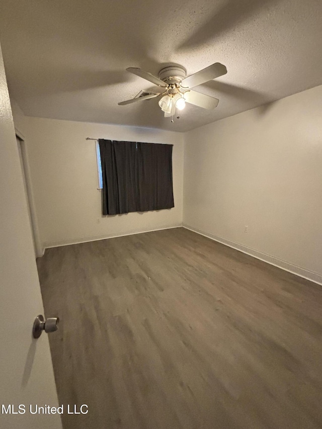 spare room with a textured ceiling, dark wood-type flooring, and ceiling fan