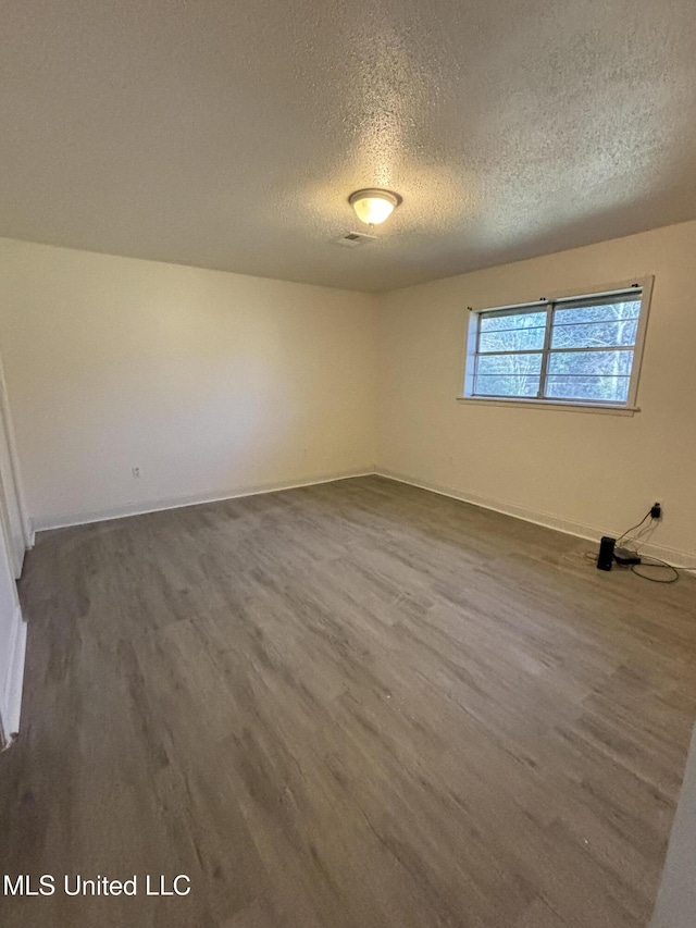 spare room with hardwood / wood-style floors and a textured ceiling