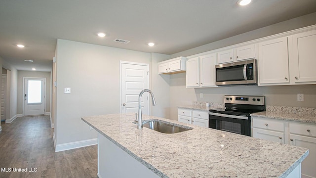 32 Crown Dr, Lucedale, MS 39452 - kitchen featuring stainless steel microwave, electric range, an island with sink, white cabinetry, and light wood-type flooring