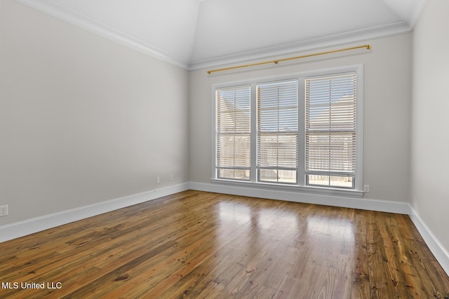 empty room featuring plenty of natural light, wood-type flooring, vaulted ceiling, and ornamental molding