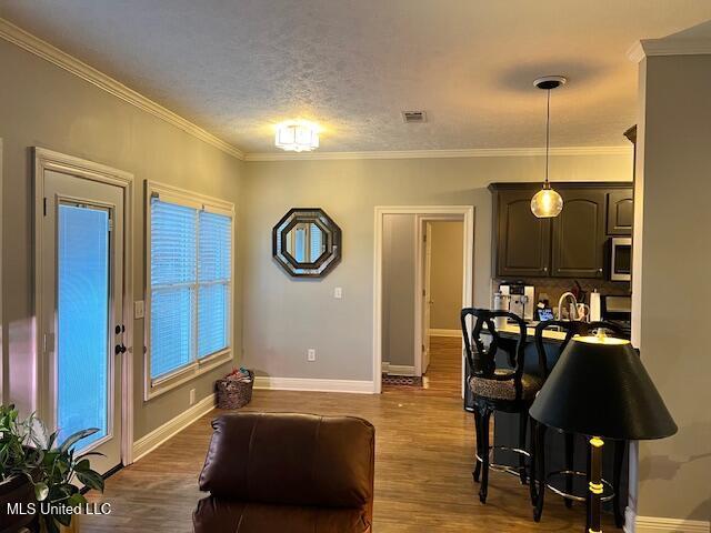 living room with a textured ceiling, hardwood / wood-style floors, and ornamental molding