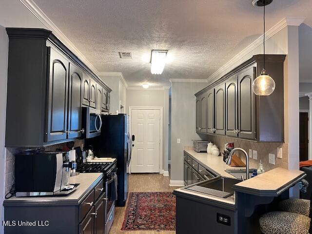 kitchen featuring appliances with stainless steel finishes, crown molding, a textured ceiling, dark wood-type flooring, and sink