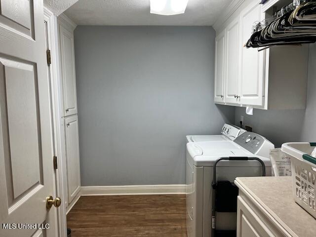 laundry room featuring washer and dryer, cabinets, and dark hardwood / wood-style floors