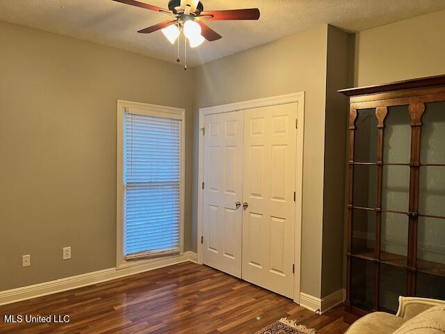 unfurnished bedroom featuring ceiling fan, dark hardwood / wood-style flooring, a closet, and a textured ceiling