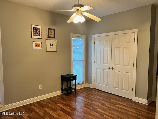 unfurnished bedroom with ceiling fan, a closet, and dark hardwood / wood-style floors