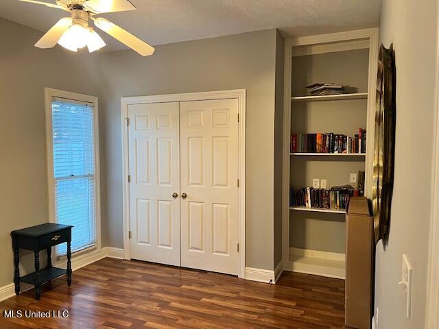 bedroom featuring ceiling fan, dark hardwood / wood-style flooring, a closet, and a textured ceiling