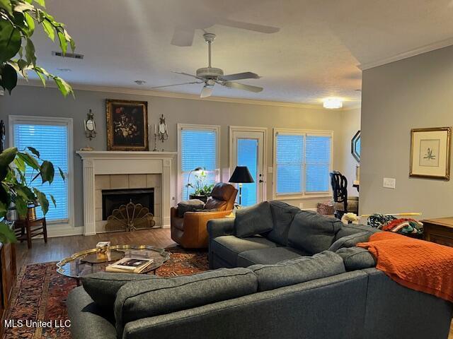 living room featuring hardwood / wood-style floors, a fireplace, ceiling fan, and ornamental molding