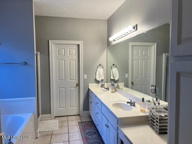 bathroom with a bathing tub, a textured ceiling, tile patterned floors, and vanity