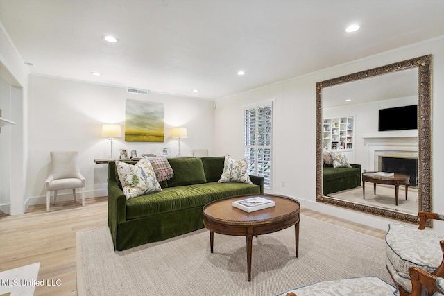 living area with light wood-style flooring, recessed lighting, visible vents, crown molding, and a fireplace
