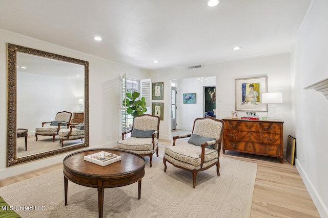 sitting room featuring light wood-type flooring, visible vents, baseboards, ornamental molding, and recessed lighting