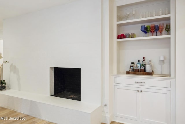 details with a dry bar, a tile fireplace, and wood finished floors