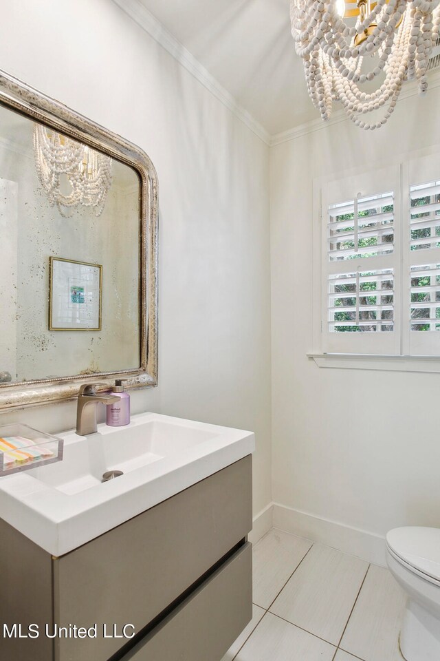 bathroom with a chandelier, toilet, ornamental molding, vanity, and tile patterned flooring